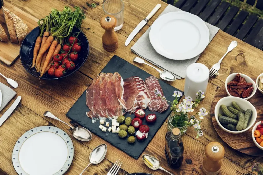 Gedekte houten tafel met vleeswaren, kaas en groenten van Ons Ambacht
