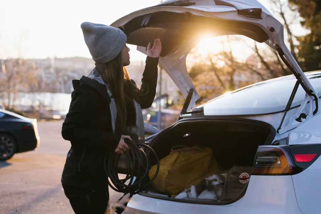 Vrouw met laadkabel bij de kofferbak van haar elektrische auto