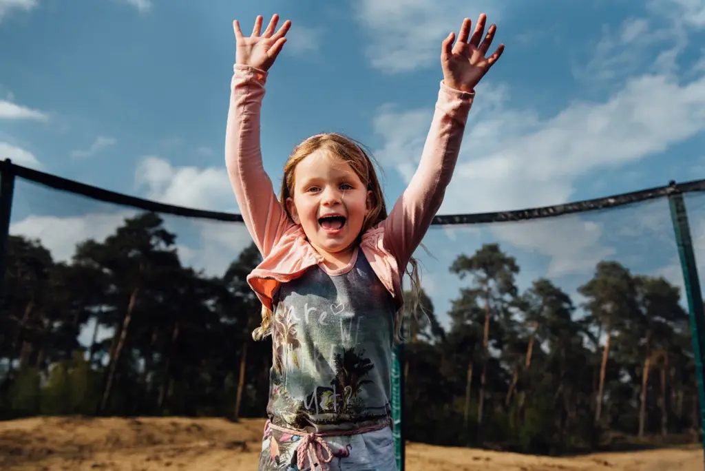Meisje met opgeheven armen bij het vangnet van een Etan-trampoline