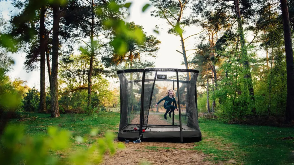 Ingegraven Etan-trampoline met volledig veiligheidsnet, kind springt binnen het net