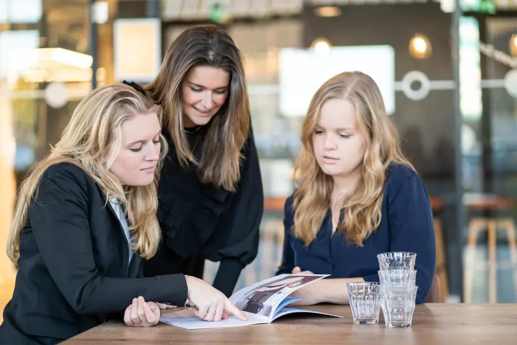 Drie collega's van Strooploos bekijken samen een magazine aan tafel