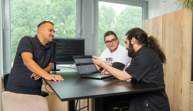 Drie van onze developers overleggen aan tafel over een koppeling